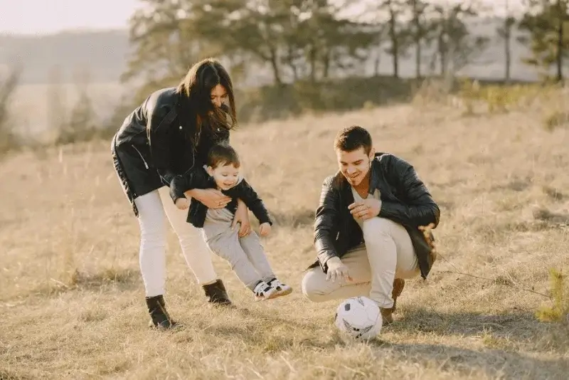 a family playing with a soccer ball in a field